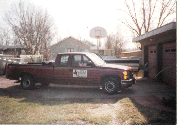 Old red Chevy with JC Roofing logo on the side parked in a residential driveway